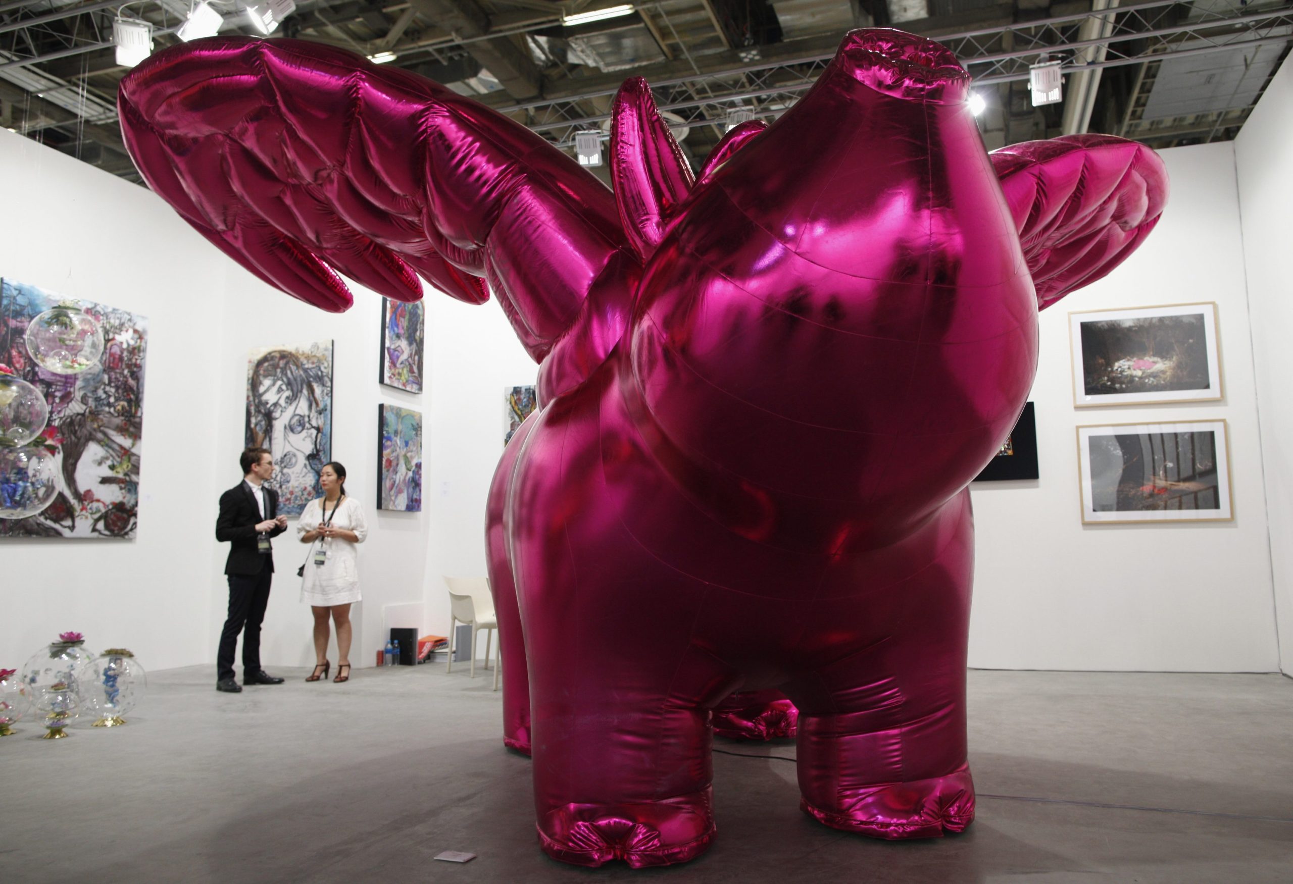 Gallery staff stand next to "Love Me", an inflatable pig with wings, by South Korean artist Choi Jeong-hwa, during a preview of the Art Stage Singapore